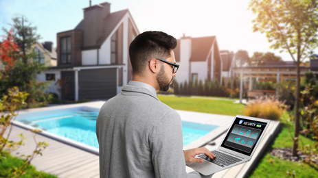 Image of Young man using home security app at backyard