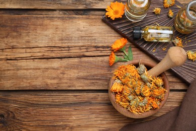 Photo of Dry calendula flowers and bottles with tincture on wooden table, flat lay. Space for text