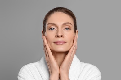 Photo of Woman massaging her face on grey background