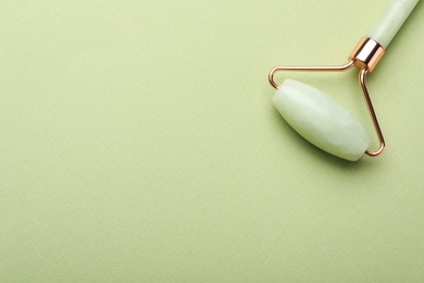 Photo of Natural face roller on green background, top view. Space for text
