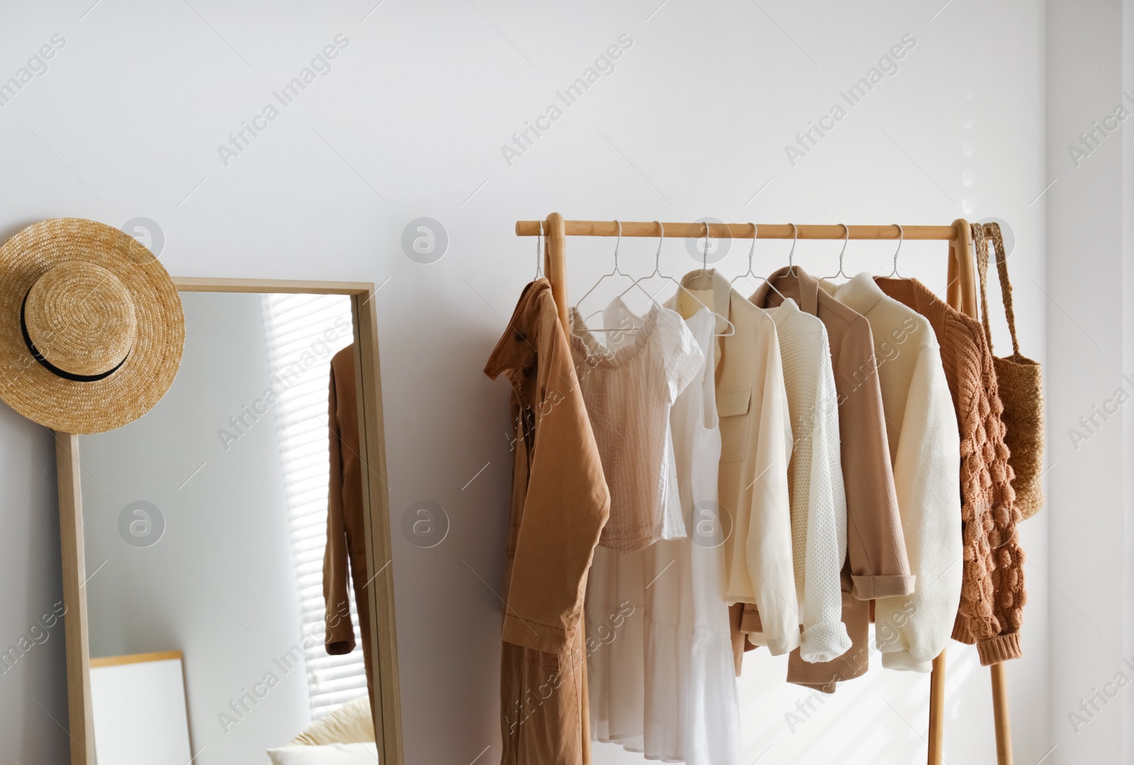 Photo of Rack with stylish women's clothes in dressing room. Modern interior design