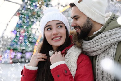 Happy young couple spending time together at winter fair. Christmas celebration