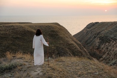 Photo of Jesus Christ on hills at sunset, back view. Space for text