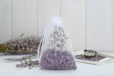 Photo of Scented sachet with dried lavender flowers on white table