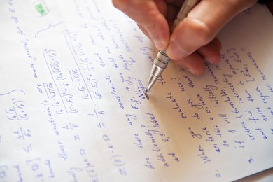Photo of Student writing mathematical calculations on paper, closeup