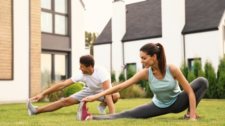 Photo of Sporty couple practicing morning yoga at backyard. Healthy lifestyle