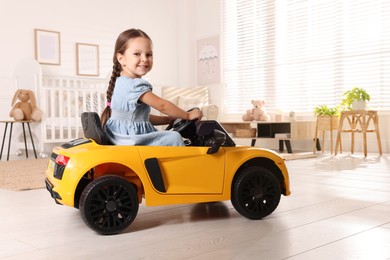 Photo of Adorable child driving toy car in room at home