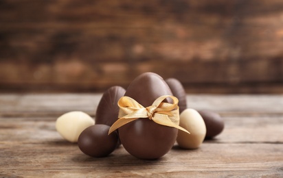 Photo of Sweet chocolate eggs on wooden table. Space for text