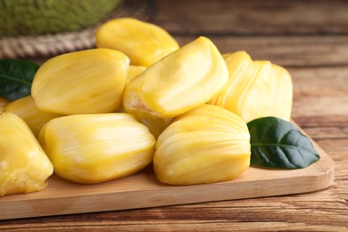 Photo of Fresh exotic jackfruit bulbs on wooden table, closeup