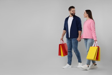 Photo of Happy couple with shopping bags on grey background. Space for text