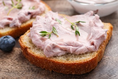 Photo of Tasty sandwich with cream cheese and thyme on wooden table, closeup