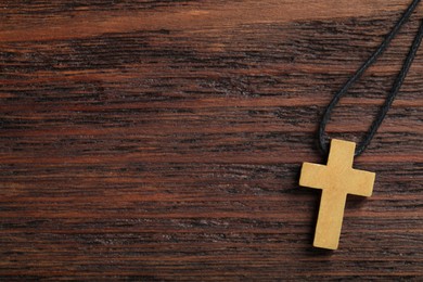 Photo of Wooden Christian cross on table, top view. Space for text