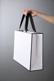 Photo of Woman holding paper bag on grey background, closeup. Mockup for design