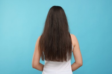 Photo of Woman with damaged hair before treatment on light blue background, back view