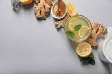 Photo of Delicious ginger tea and ingredients on light grey background, flat lay. Space for text