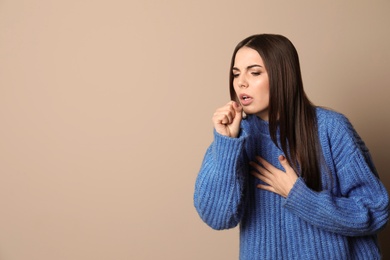 Photo of Beautiful young woman coughing against color background. Space for text