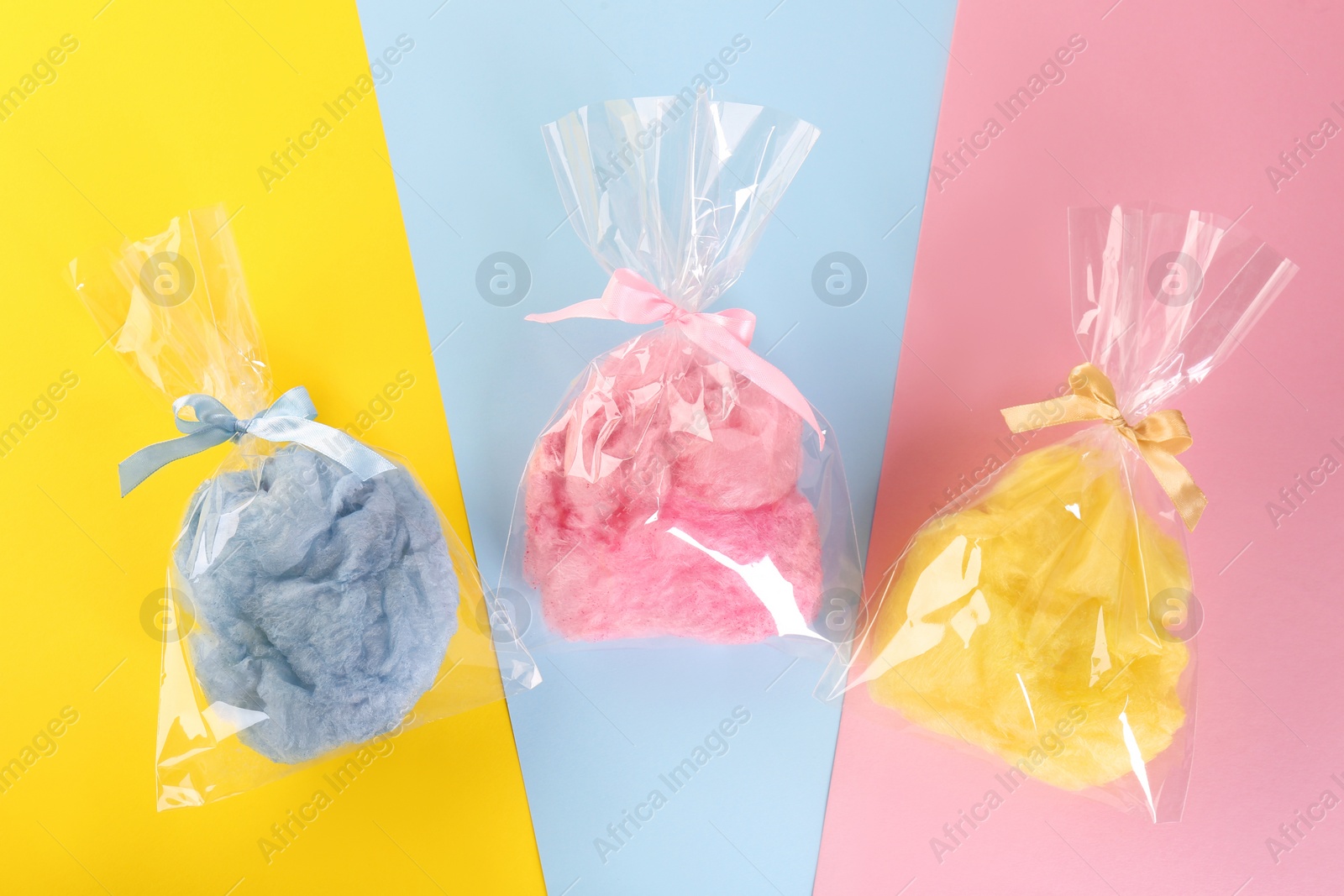 Photo of Packaged sweet cotton candies on color background, flat lay