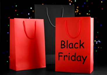 Photo of Paper shopping bags against blurred lights. Black Friday sale