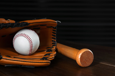 Photo of Leather baseball ball, bat and glove on wooden table