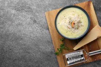 Photo of Delicious cream soup with parmesan cheese and croutons in bowl on grey table, top view. Space for text