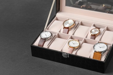 Photo of Jewelry box with many different wristwatches on dark gray background, space for text