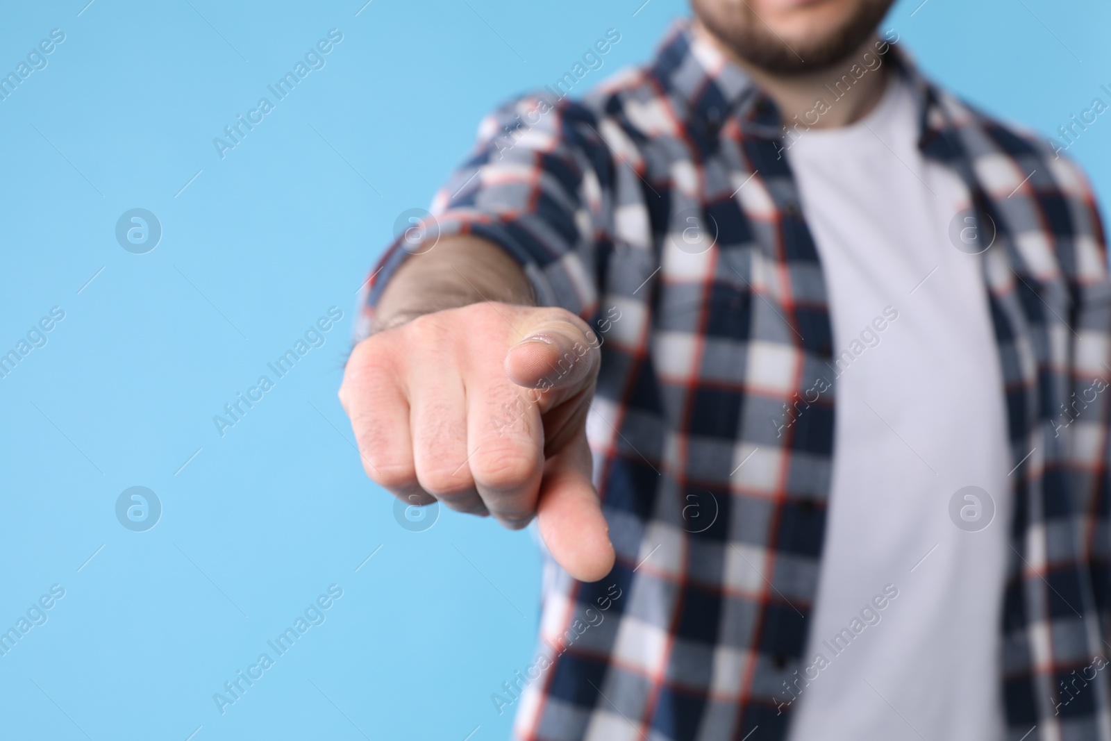 Photo of Man pointing with index finger on light blue background, closeup