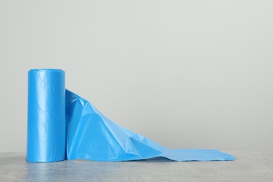 Photo of Roll of color garbage bags on table against light background. Space for text