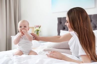 Photo of Happy mother with little baby on bed at home
