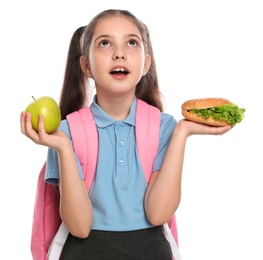 Photo of Emotional girl with burger and apple on white background. Healthy food for school lunch