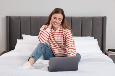 Photo of Happy woman with laptop on bed in bedroom