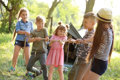 Photo of Little children pulling rope outdoors. Summer camp