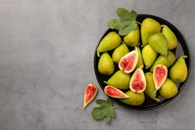 Photo of Cut and whole green figs on light gray table, flat lay. Space for text