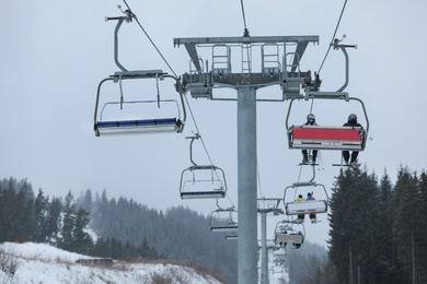 Photo of Chairlift with people at ski resort. Winter vacation