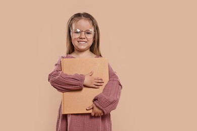Photo of Cute little girl with book on beige background