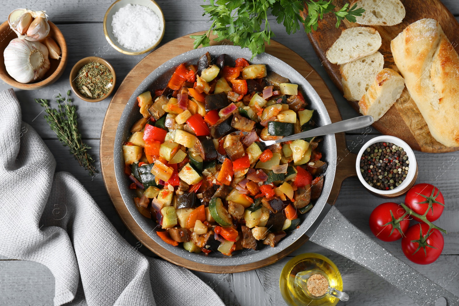 Photo of Delicious ratatouille and ingredients on grey wooden table, flat lay