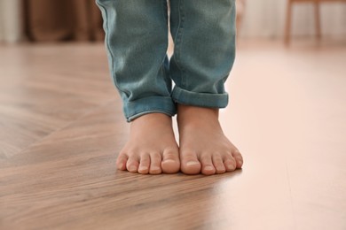 Photo of Little child walking barefoot at home, closeup. Floor heating concept