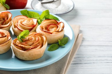 Photo of Freshly baked apple roses on white wooden table, space for text. Beautiful dessert