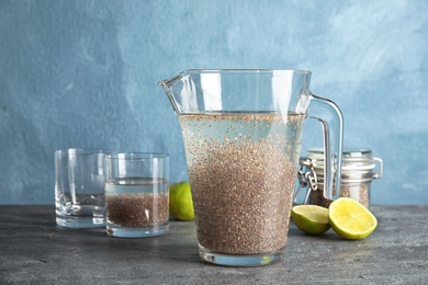 Photo of Composition with jug of water and chia seeds on table against color background