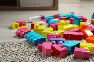 Photo of Colorful plastic building blocks on floor indoors, space for text