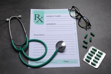 Photo of Medical prescription form, stethoscope, pills and glasses on dark grey table
