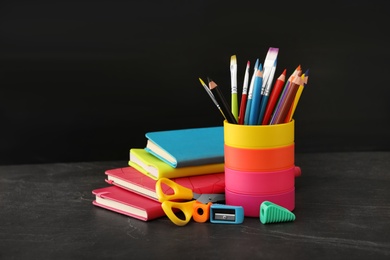 Photo of Different school stationery on stone table near blackboard. Back to school