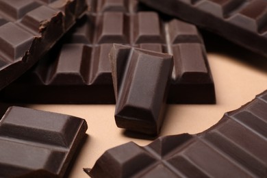 Photo of Pieces of delicious chocolate bars on beige background, closeup