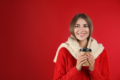 Photo of Happy beautiful woman with paper cup of mulled wine on red background. Space for text