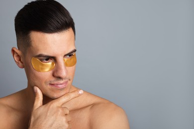 Photo of Man with golden under eye patches on grey background. Space for text