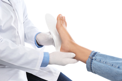 Photo of Male orthopedist fitting insole on patient's foot against white background, closeup