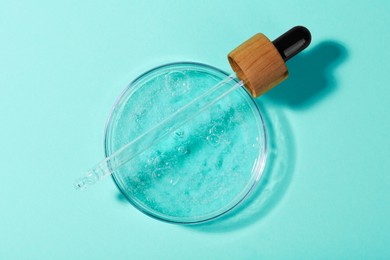 Petri dish with liquid sample and pipette on green background, top view