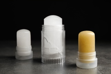 Photo of Natural crystal alum deodorants on grey table against black background