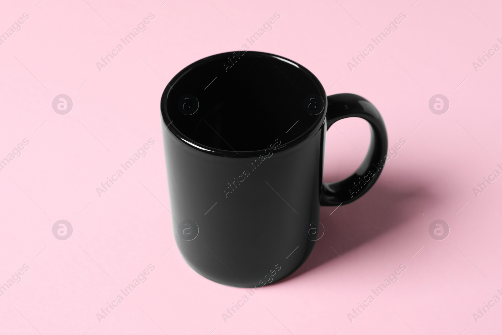 One black ceramic mug on pink background Photo of One black ceramic mug on pink background