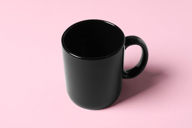 Photo of One black ceramic mug on pink background
