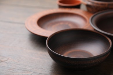 Photo of Set of clay dishes on wooden table, space for text. Cooking utensils